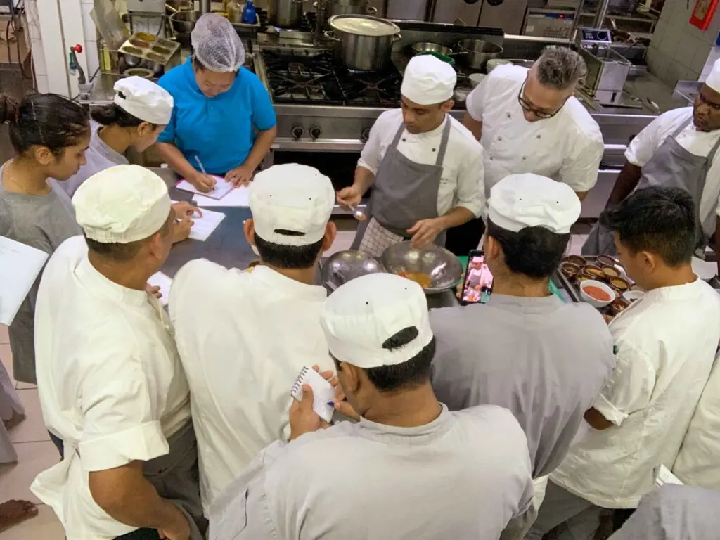 A professional kitchen team receiving on-site **chef training** and mentorship for a new restaurant opening.